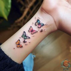 a woman's wrist tattoo with butterflies on the left side of her arm,