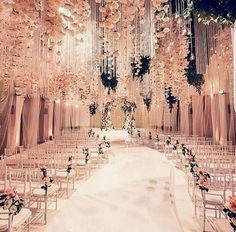 a wedding ceremony setup with white chairs and chandeliers hanging from the ceiling,