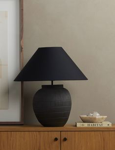 a black lamp sitting on top of a wooden dresser