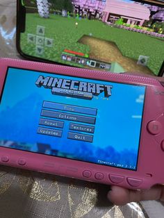 a person holding a pink nintendo wii game controller in front of a computer screen with the words minecraft on it