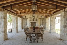 an outdoor dining area with stone walls and wooden ceiling beams, surrounded by chairs and tables