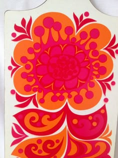 an orange and pink flower is on a white board with red swirls around it