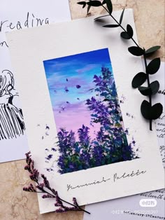 some paper with pictures on it next to flowers and leaves, one has a purple sky in the background