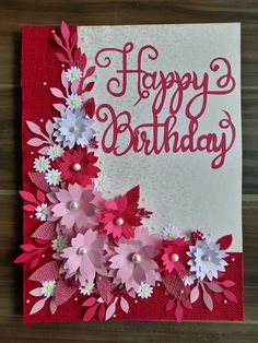 a birthday card with pink and white paper flowers on it's side, sitting on a table