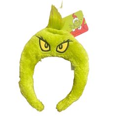 a green headband with yellow eyes and long hair on it's side, in front of a white background