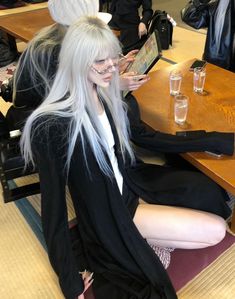 a woman with long white hair sitting at a table