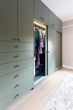 an open closet with clothes on hangers and rug in the floor next to it