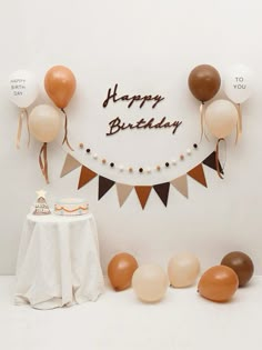 a birthday party with balloons, cake and bunting banner on the wall in front of it