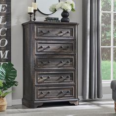 a bedroom with a dresser and mirror next to a chair in front of a window