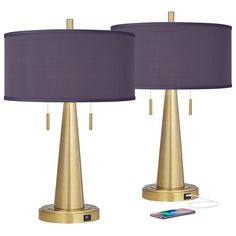 two gold and purple lamps next to each other with a cell phone plugged in