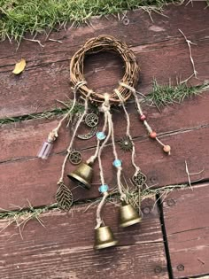 some bells are hanging from a rope on a wooden floor with grass and leaves around them