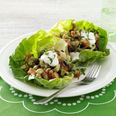 two lettuce wraps with dressing on a plate next to a glass of water