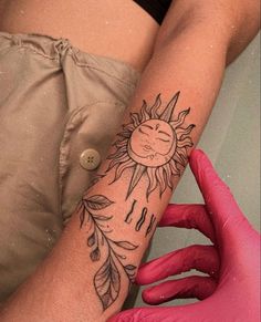 a woman's arm with a sun tattoo on it