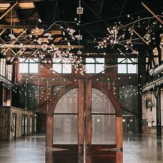 an open wooden door in the middle of a room with lights hanging from it's ceiling