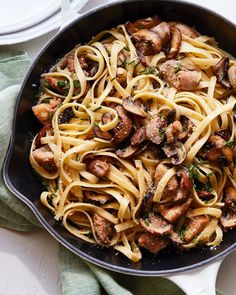 a pan filled with pasta and mushrooms on top of a table