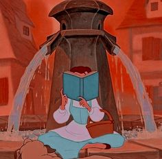 a woman sitting on the ground reading a book in front of an open fire hydrant