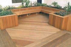 a wooden bench sitting on top of a hard wood floor next to potted plants