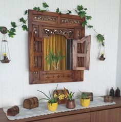 a wooden mirror hanging on the wall above a dresser with potted plants and other decorations