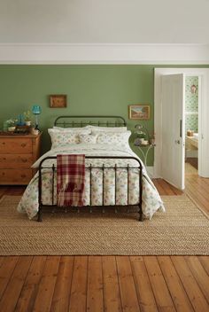 a bedroom with green walls and wooden floors