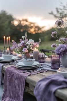 the table is set with purple flowers and candles