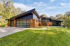 a modern house in the middle of a lush green field with lots of trees and grass