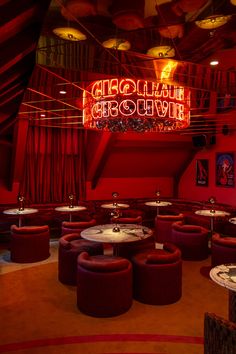 the inside of a restaurant with round tables and stools in front of red curtains