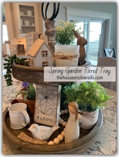 a tray filled with potted plants and other items on top of a table next to a sign that says spring garden tiered tray