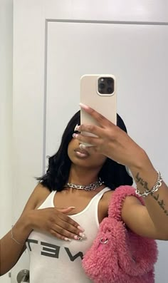 a woman taking a selfie in front of a mirror wearing a pink furry vest