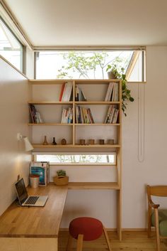 a laptop computer sitting on top of a wooden desk in front of a bookshelf