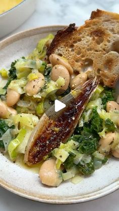 a white plate topped with lots of food on top of a table next to bread