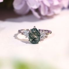 a close up of a ring on a table with flowers in the background