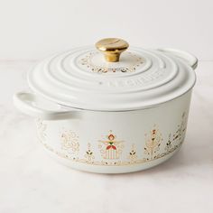 a white casserole dish with gold trimmings and a golden knob on top