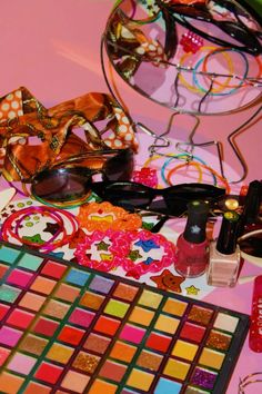 a table topped with lots of different types of makeup and eyeglasses on top of it