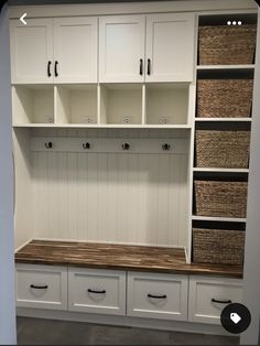 a room with white cabinets and baskets on the wall