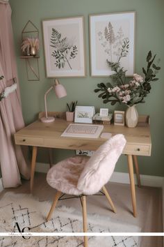 a desk with a laptop computer on top of it next to a pink chair and flowers