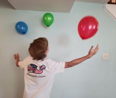 a young boy is playing with balloons on the wall