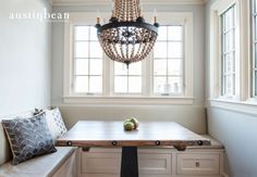 a dining room table and bench with a chandelier hanging from the ceiling