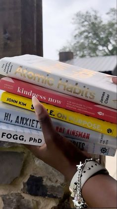 a stack of books sitting on top of each other in front of a brick wall