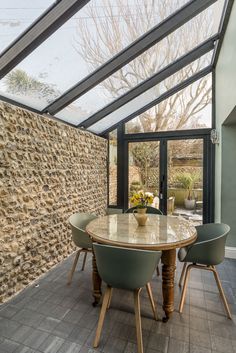 a dining room table with four chairs and a large glass roof over the patio area