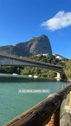 a bridge that is over water with mountains in the backgroung and blue sky