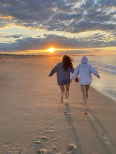 two people walking on the beach with footprints in the sand and one person holding hands