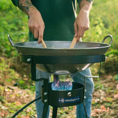 a man is cooking on an outdoor grill with tongs in his hand while standing outside