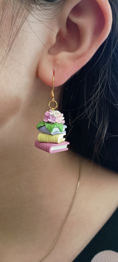 a close up of a person wearing some kind of book earrings with books on it