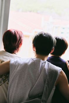 three people sitting on a couch looking out the window