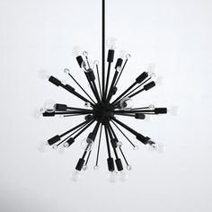 a black chandelier with many bulbs hanging from it's center and the lights turned on