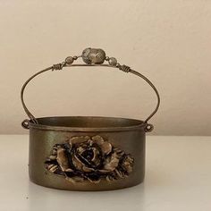 a metal pot with a flower on it