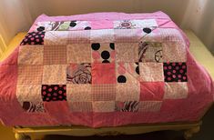 a pink and black patchwork quilt sitting on top of a bed