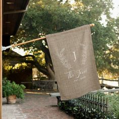 a burlap banner hanging from a clothes line on a brick walkway in front of a house