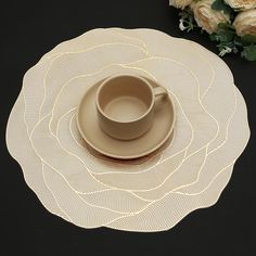 a cup and saucer sitting on top of a placemat with flowers in the background