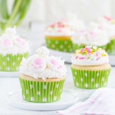 some cupcakes with white frosting and sprinkles are on a plate